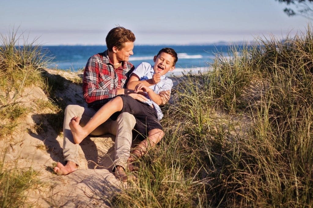 Man and Boy Sitting on Floor Near Body of Water. Children's Naturopath. Brisbane Livewell Clinic.