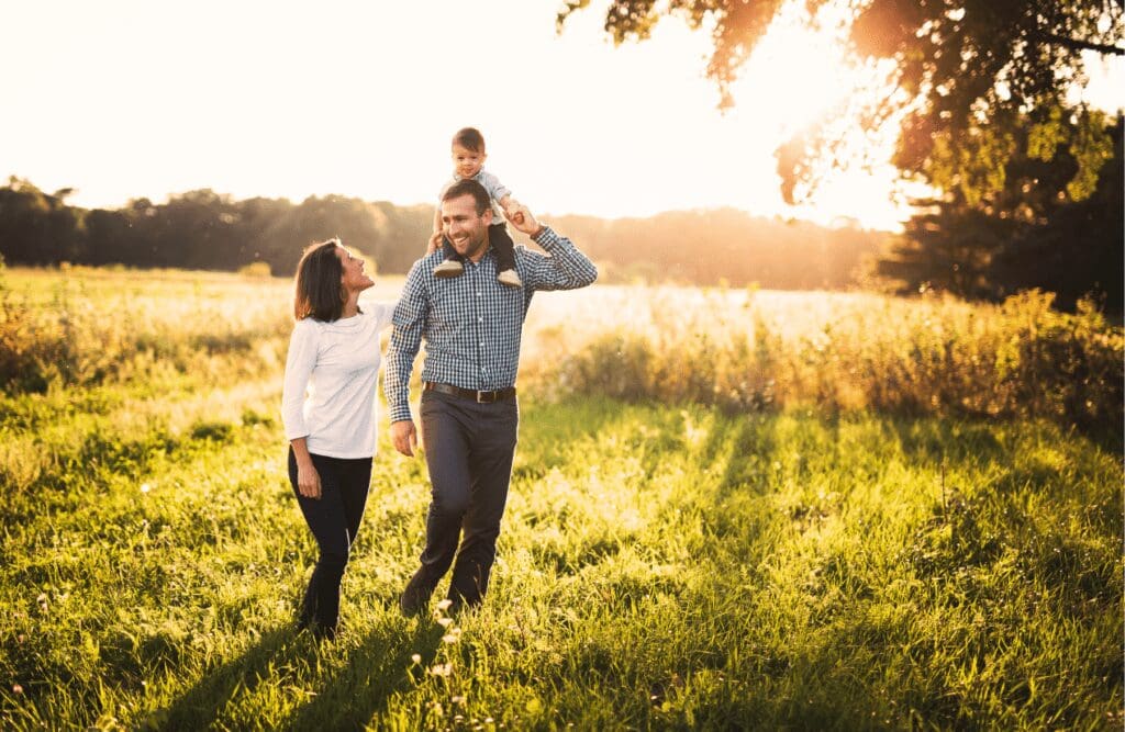 Family walking in the field, with child on father's shoulders. Daily ritual gut health.