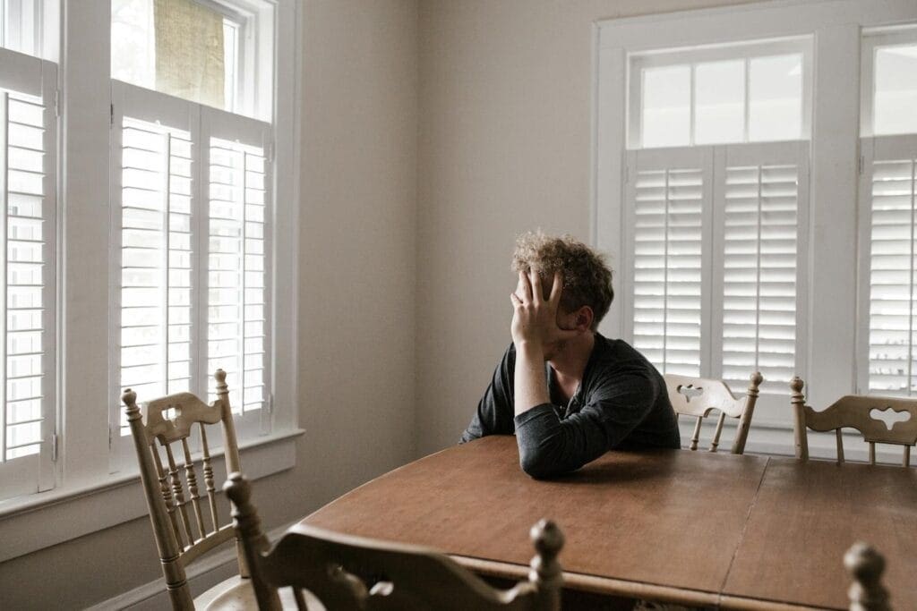 Photo of Man Leaning on Wooden Table. Does Hypnotherapy for Anxiety Work? Brain Fog. Brisbane Livewell Clinic