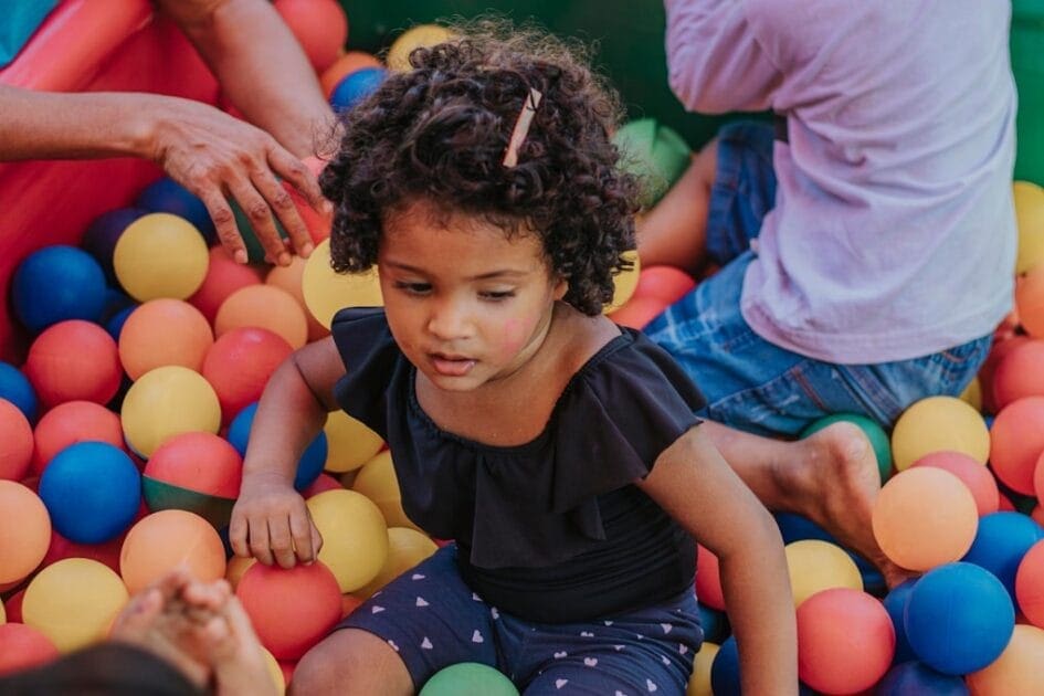 Girl in black shirt and blue denim shorts sitting on yellow and pink balloons. Gut Health Specialist Brisbane