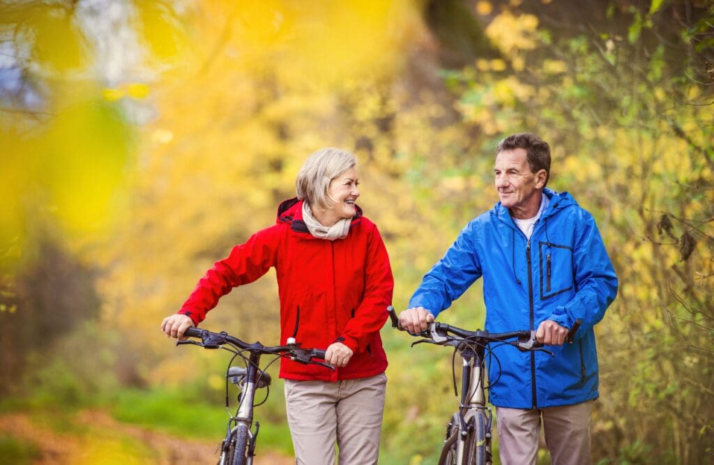 Couple around 60 walking with bike. Exercise. Leaky Gut Syndrome. What is Leaky Gut Australia. Lose Weight Hypnotherapy. Brisbane Livewell Clinic
