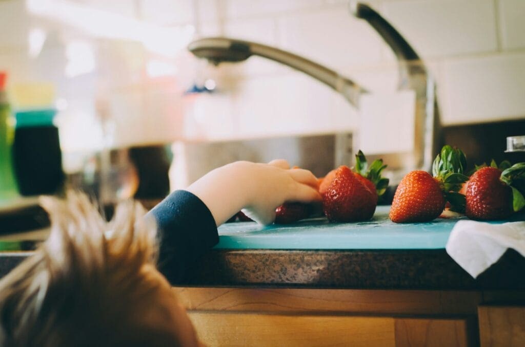 Child picking strawberries in kitchen. Heavy Metal and Parasite Detox. Brisbane Livewell Clinic