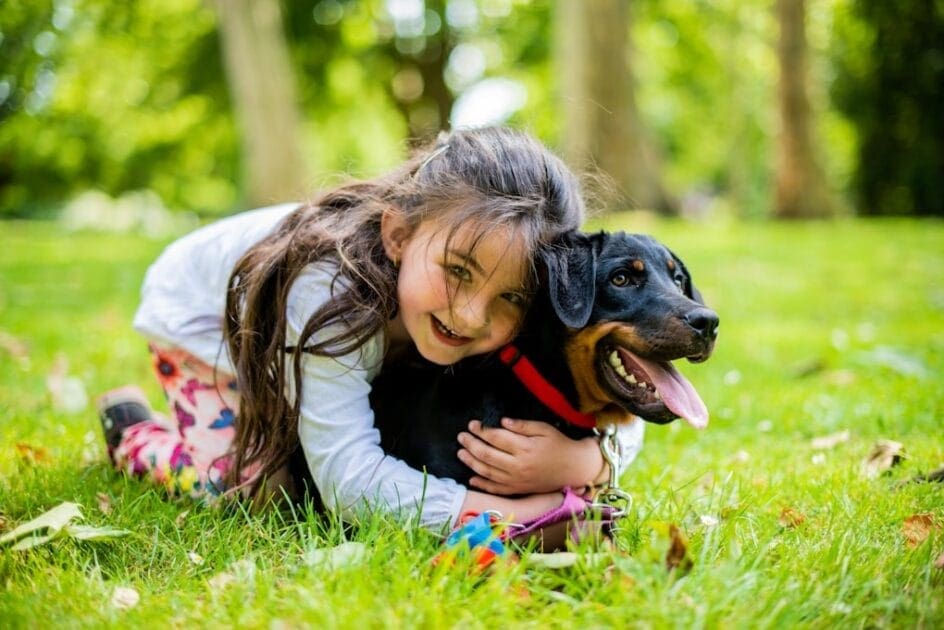Girl with dark hair hugging dog on green grass field. DNA Genetic Methylation Testing in Brisbane