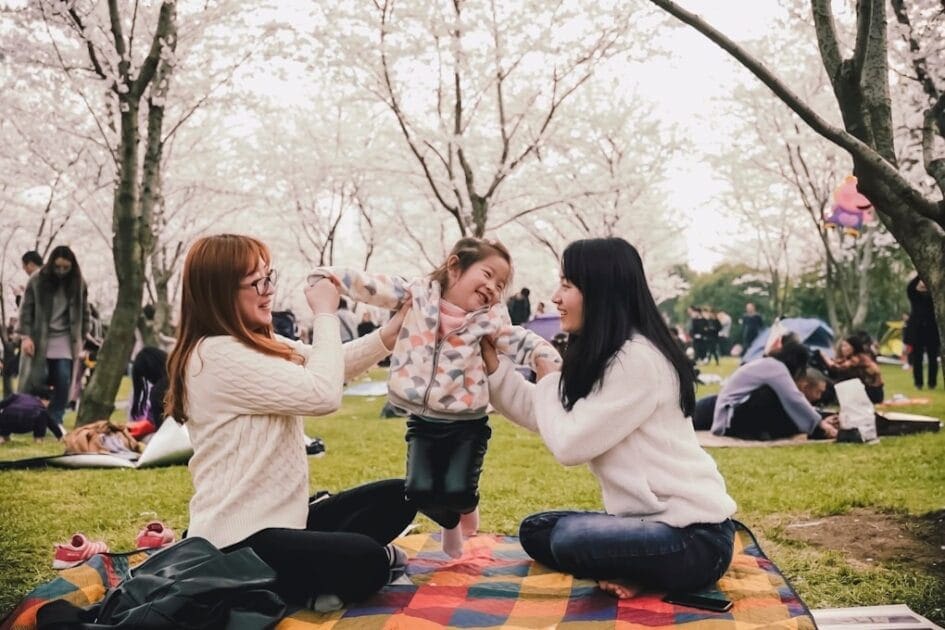 Two women sitting on top of a blanket in a park with their child. Genetic Methylation Test Brisbane
