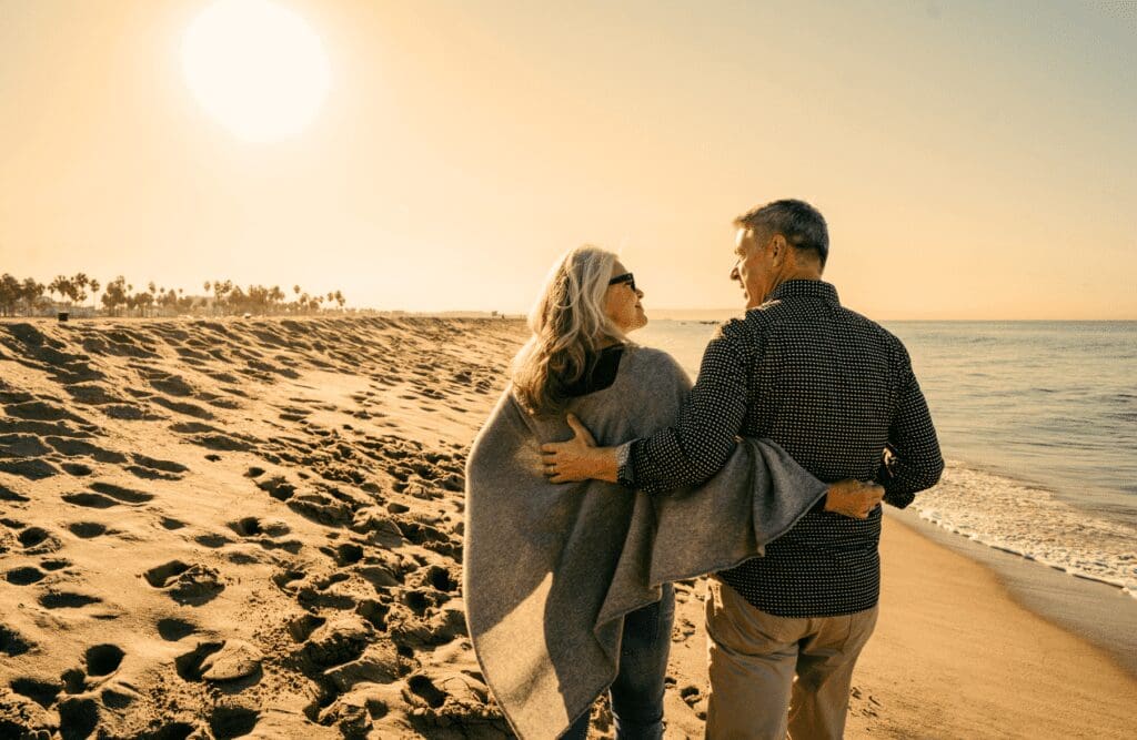 Couple around 60 walking o the beach. Naturopaths. Brisbane Livewell Clinic