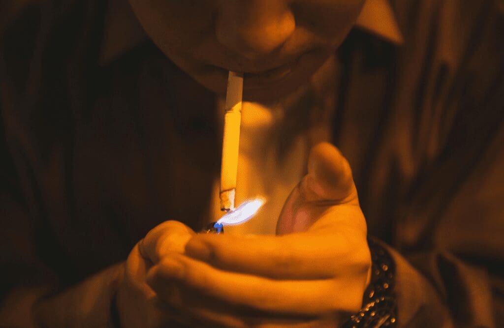 Man lighting a cigarette to smoke. How much is Hypnotherapy. Brisbane Livewell Clinic