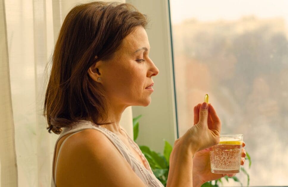 Woman holding a glass of water and vitamins. Thyroid Health. Brisbane Livewell Clinic