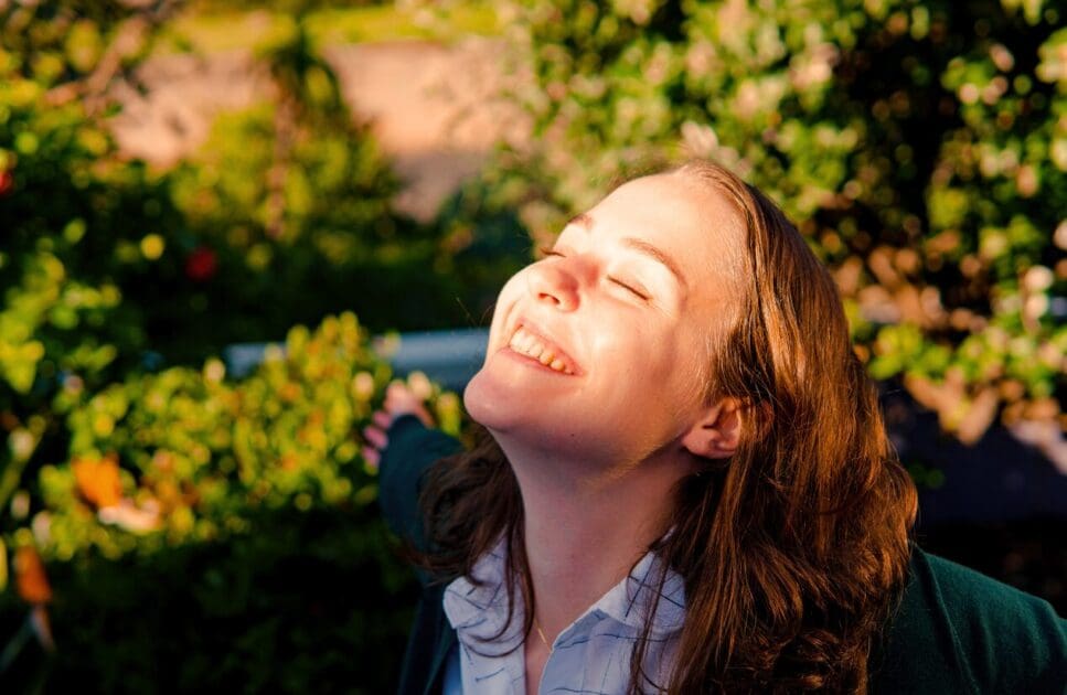Woman smiles while looking up at the sun. Gut Health Test Australia. Clinical Hypnotherapy Brisbane. Brisbane Livewell Clinic