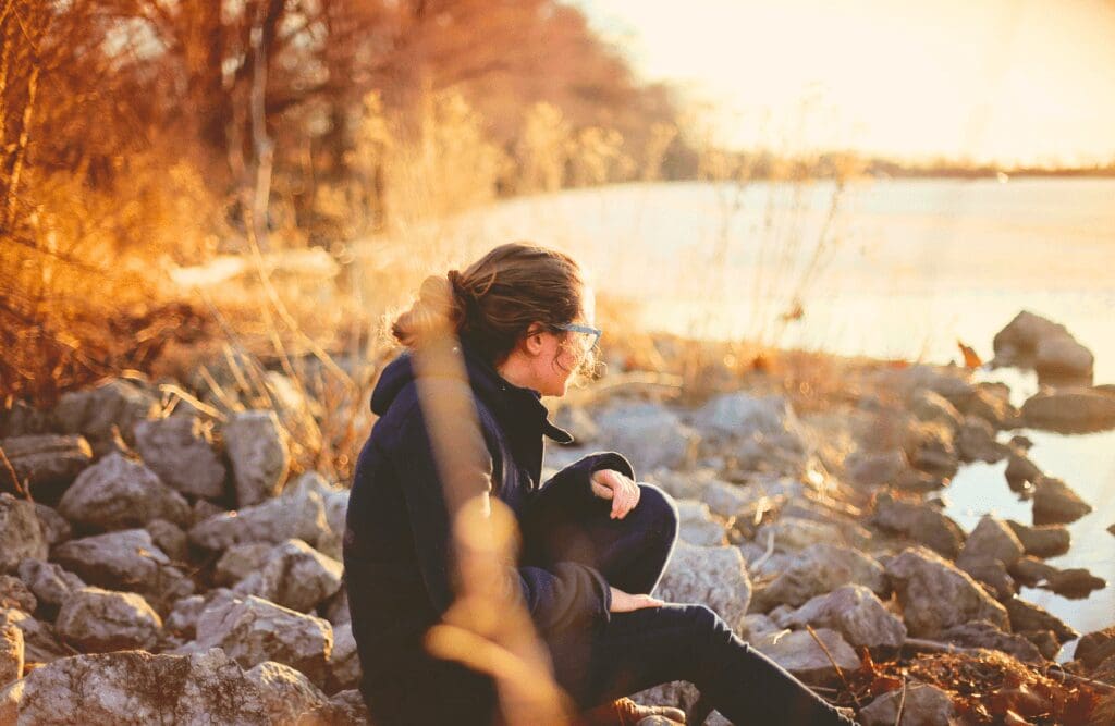 Woman sitting on a rock beside a river. Gut brain connection. Hypnotherapy for Alcohol Addiction. Methylation Test Near Me. Brisbane Livewell Clinic