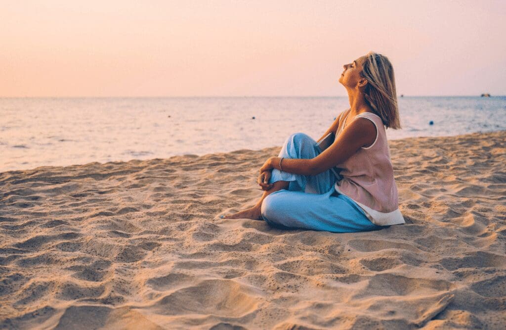 Woman sitting on the seashore. Menopause. Osteopath for Posture and Alignment. Brisbane Livewell Clinic