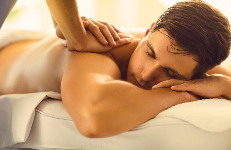 Young man lying on massage table enjoying back massage. Remedial Massage Near Me. Remedial Massage Brisbane. Brisbane Livewell Clinic