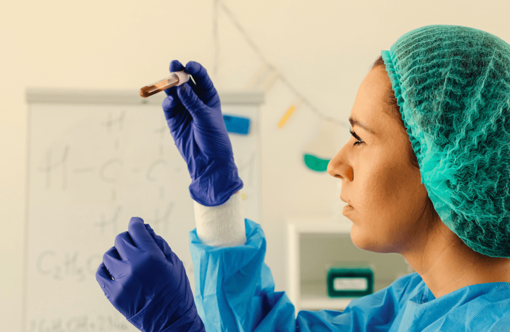 Woman looking at a blood sample on a test tube. Blood Analysis Cost. Brisbane Livewell Clinic