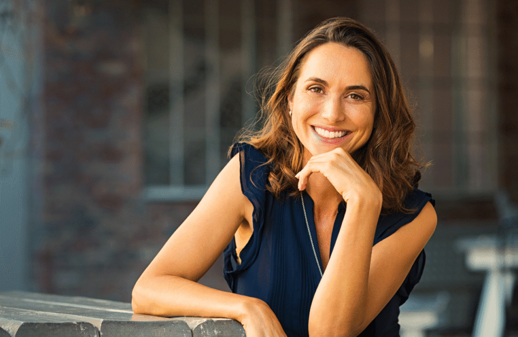 Smiling woman sitting outside a coffee shop. At home hormone testing. Thyroid health. Healthy thyroid. Hormone Testing Brisbane. DUTCH Testing Near Me. Hyperthyroidism. Is Osteopathy Good for Back Pain. Brisbane Livewell Clinic