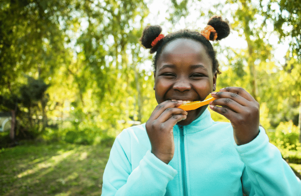 Young girl happily eating a slice of fruit. Mood & Food. Children's Naturopath. Brisbane Livewell Clinic. Clinical Nutritionist Carina. Brisbane Livewell Clinic