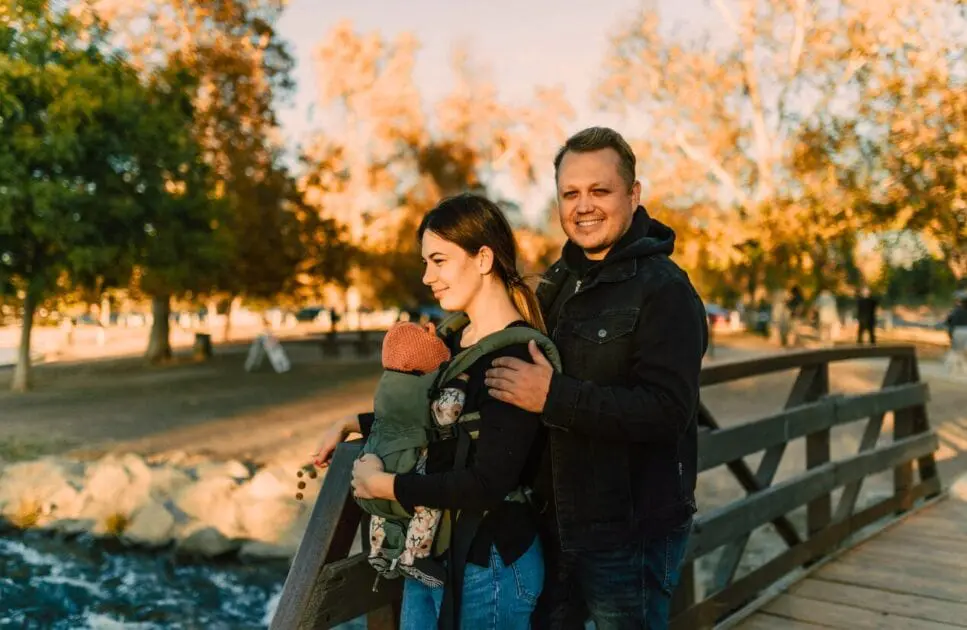 Couple carrying their baby while standing on the wooden bridge. Counselling Carindale. Brisbane Livewell Clinic. Clinical Hypnotherapy. Infant and baby colic