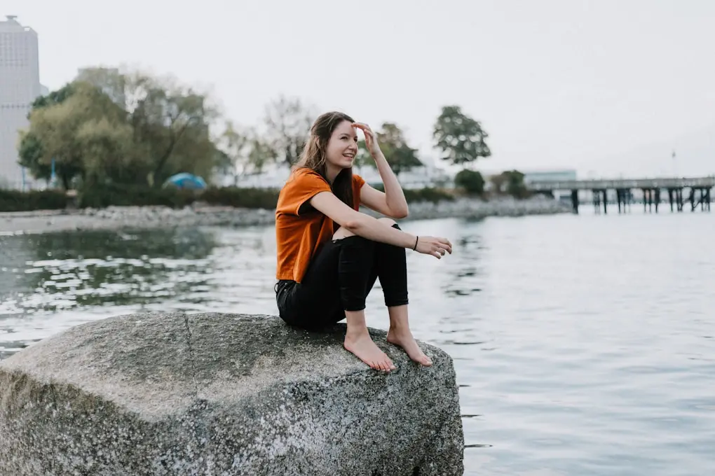 Woman sitting on a rock over a lake. Jeremy Walker - Hypnotherapist Brisbane