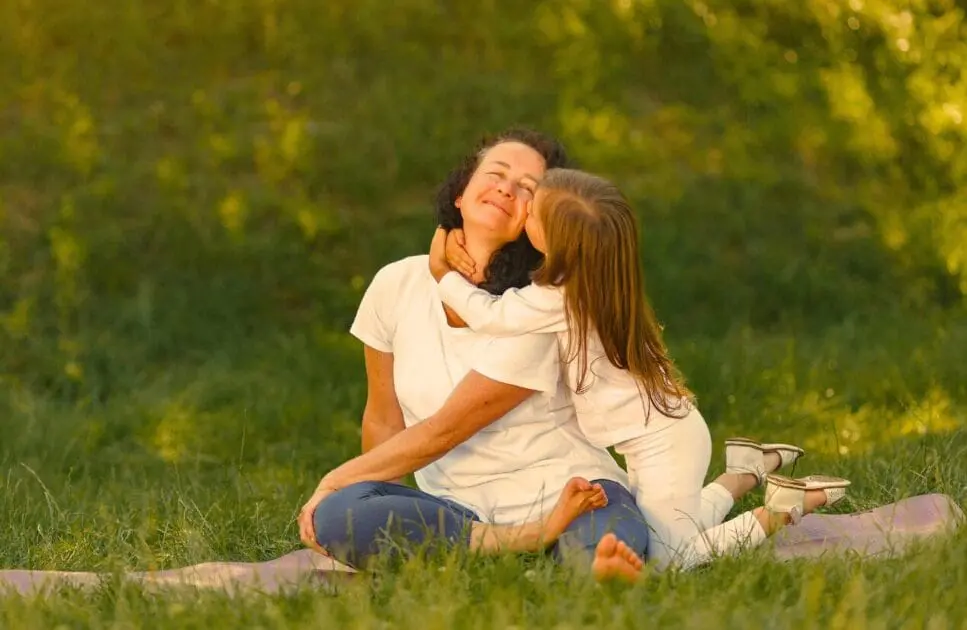 Young girl kisses her mom on the cheek while they sit on the grass. Hypnotherapy near Virginia. Naturopathic Remedies to help sleep. Hypnotherapy to Reduce Anxiety. Brisbane Livewell Clinic