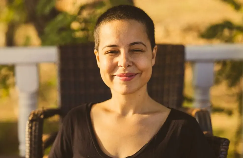 Smiling woman sitting on the chair on the balcony. Lymph Drainage. Blood Analysis Cost. Burnout Holistic Counselling. Brisbane Livewell Clinic