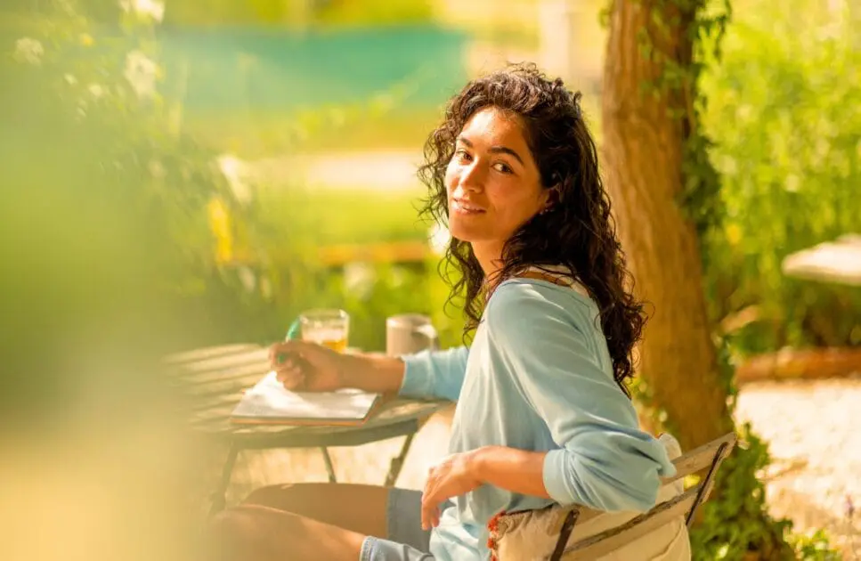 Smiling woman sitting at a table with a pen and her journal. Hypnotherapy near Geebung. Clinical Nutrients. Brisbane Livewell Clinic