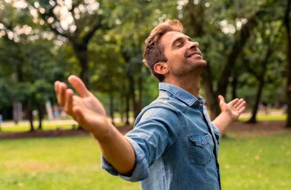 Man stands in a park with his arms outstretched. Trauma Counselling. Holistic Counselling Wavell Heights. Hypnosis for Anxiety. Brisbane Livewell Clinic