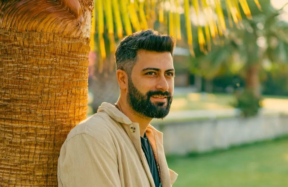 Man smiling while leaning on palm tree. Online Counselling Australia. Brisbane Livewell Clinic