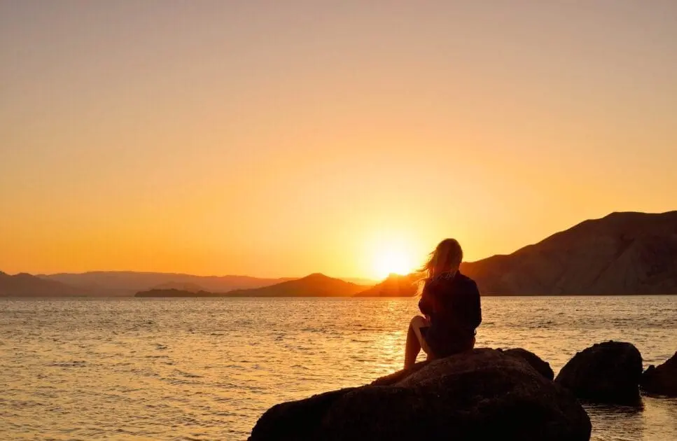 Woman sitting on a rock, watching sunset. Counselling Wooloowin. Counselling Stafford. Brisbane Livewell Clinic