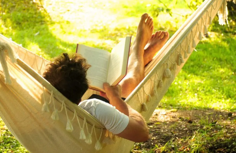 Man relaxes in a hammock while reading a book. Christmas Health Guide. Mindset Therapy Brisbane. Professional Bowen Therapy. Brisbane Livewell Clinic