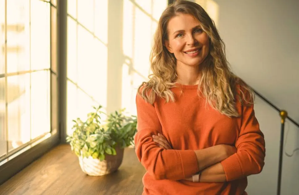 Middle-aged woman standing near the window. Lifestyle Changes Women Need. Osteopath for Back Pain. Brisbane Livewell Clinic