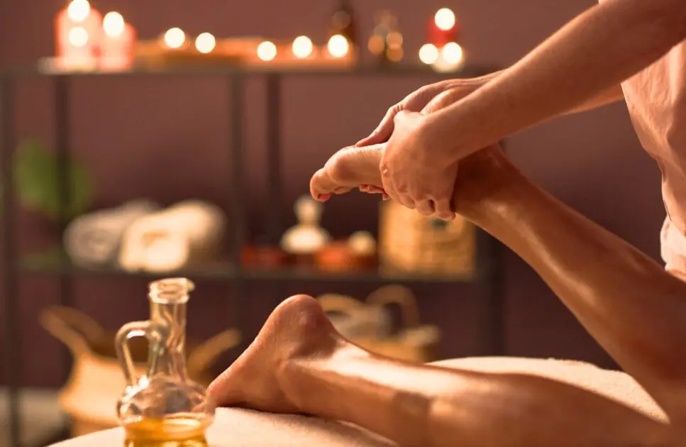 Massage therapist applying massage oil to client's feet. Benefits of Therapeutic Massage. Brisbane Livewell Clinic