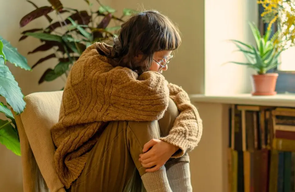 Woman hugging her knees while sitting. Brain Fog. What Causes Painful Period. Iron Deficiency. Brisbane Livewell Clinic