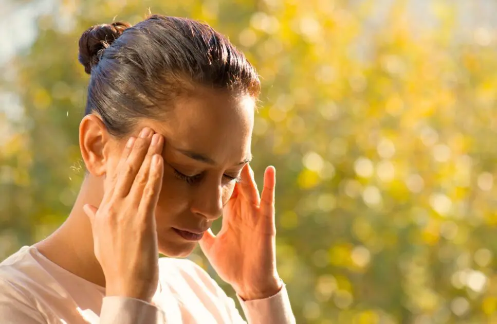 Woman holding her head, expressing discomfort. Brain Fog. Masking Rocovery Holistic Counselling. Brisbane Livewell Clinic