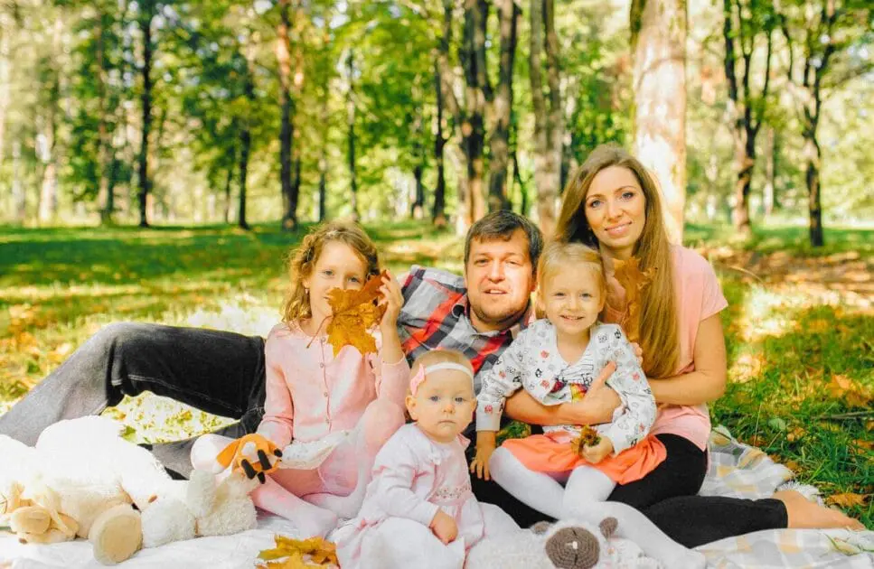 Family sitting together on a picnic blanket while enjoying a sunny day at the park. Hypnotherapy near Hendra. Brisbane Livewell Clinic