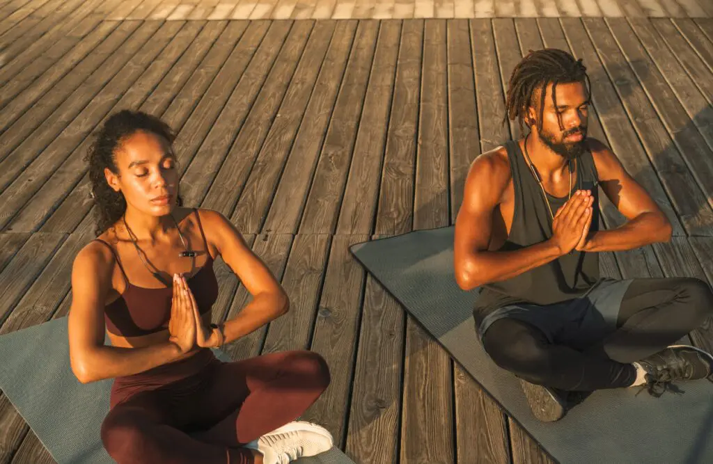 Man and woman practicing yoga outdoors on a wooden deck. Naturopathy Wavell Heights. Brisbane Livewell Clinic