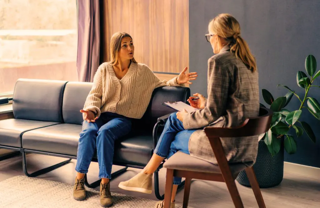 Woman sitting on the couch talking to the Naturopath. Naturopathy Wavell Heights. Therapists Brisbane. Iron Deficiency. Heavy Metal Detox Naturopath. Employee Naturopath Job. Brisbane Livewell Clinic