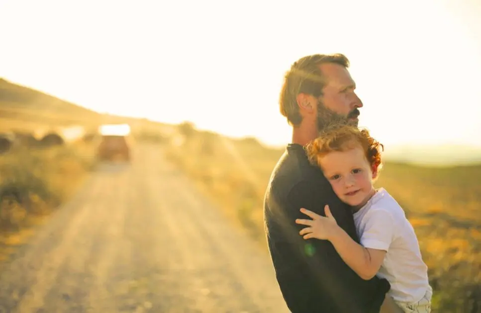 Man standing on a dirt road while carrying his son. Hypnotherapy near Kedron. Holistic Counselling Brisbane. Brisbane Livewell Clinic