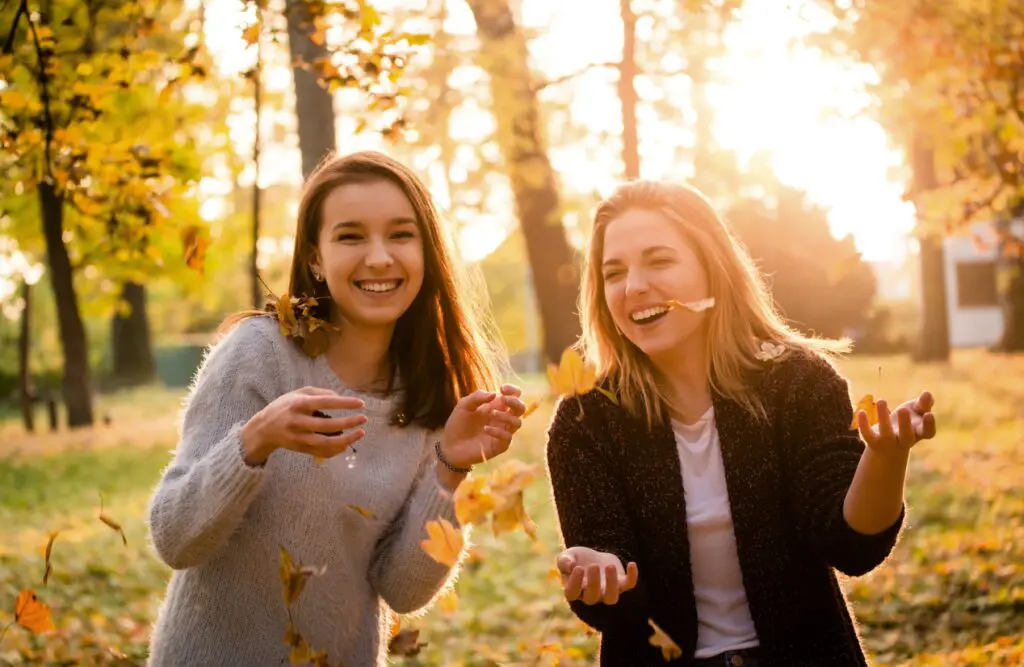 Two female friends having fun in a park filled with fallen leaves. Naturopath Cannon Hill. Naturopath Wavell Heights. Pyrrole Disorder. Brisbane Livewell Clinic