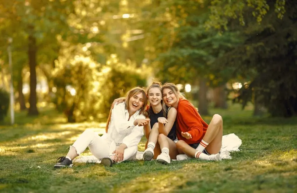 Three young women sitting together on the grass in a park. Hypnotherapy near Chermside. Brisbane Livewell Clinic