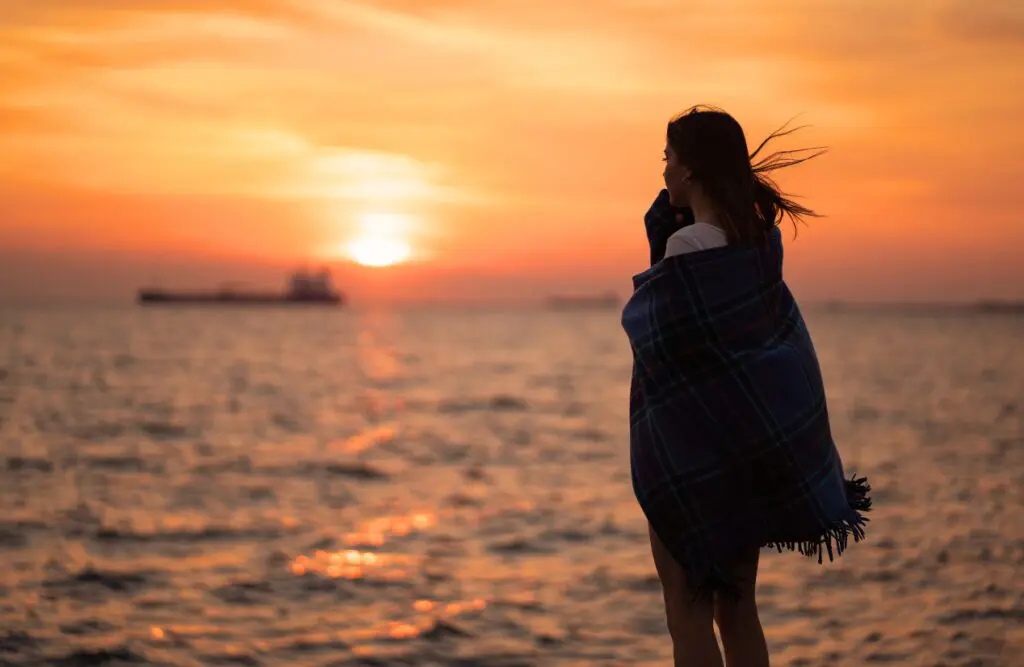 Woman standing by the sea, wrapped in blanket. Counselling Morningside. Counselling Aspley. Counselling Geebung. Brisbane Livewell Clinic