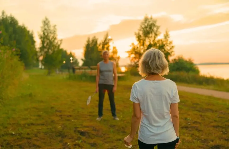 Couple playing badminton on the grass field during sunset. Couples Counselling. FAQS. Osteopath Seven Hills. Osteopath for Sports Injuries. Brisbane Livewell Clinic