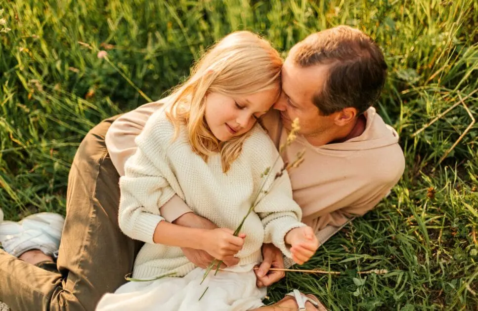Father and daughter sitting on the grass field. Hypnotherapy near Northgate. Brisbane Livewell Clinic