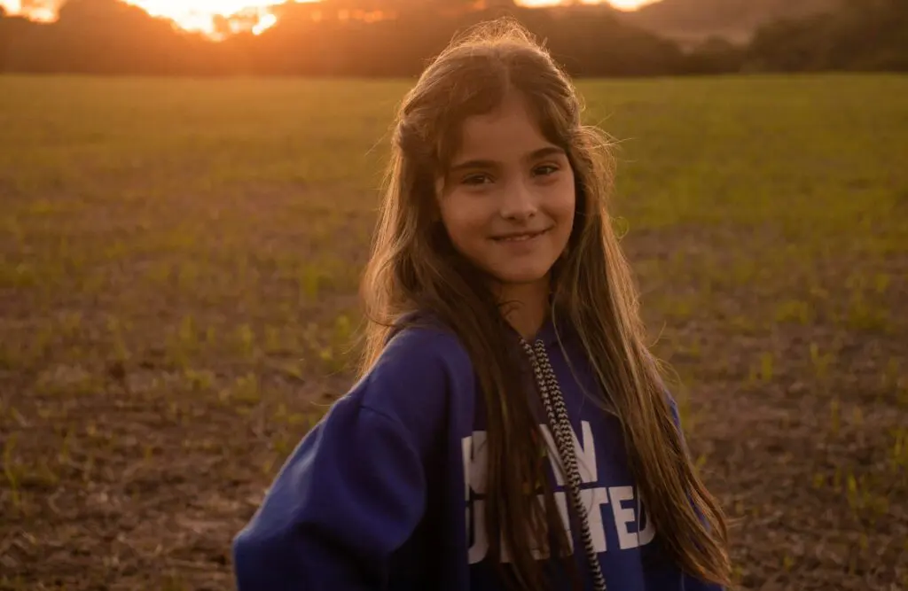 Smiling young girl stands in a field during sunset. Counselling Kedron. Brisbane Livewell Clinic